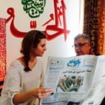 Student reading the Amman newspaper with her teacher