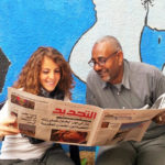 student reading the Rabat newspaper with her teacher