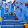 The blue city, Blue staircase and wall decorated with colourful flowerpots, Chefchaouen medina in Morocco.