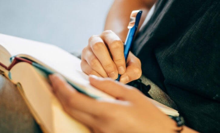 Person writing on a book